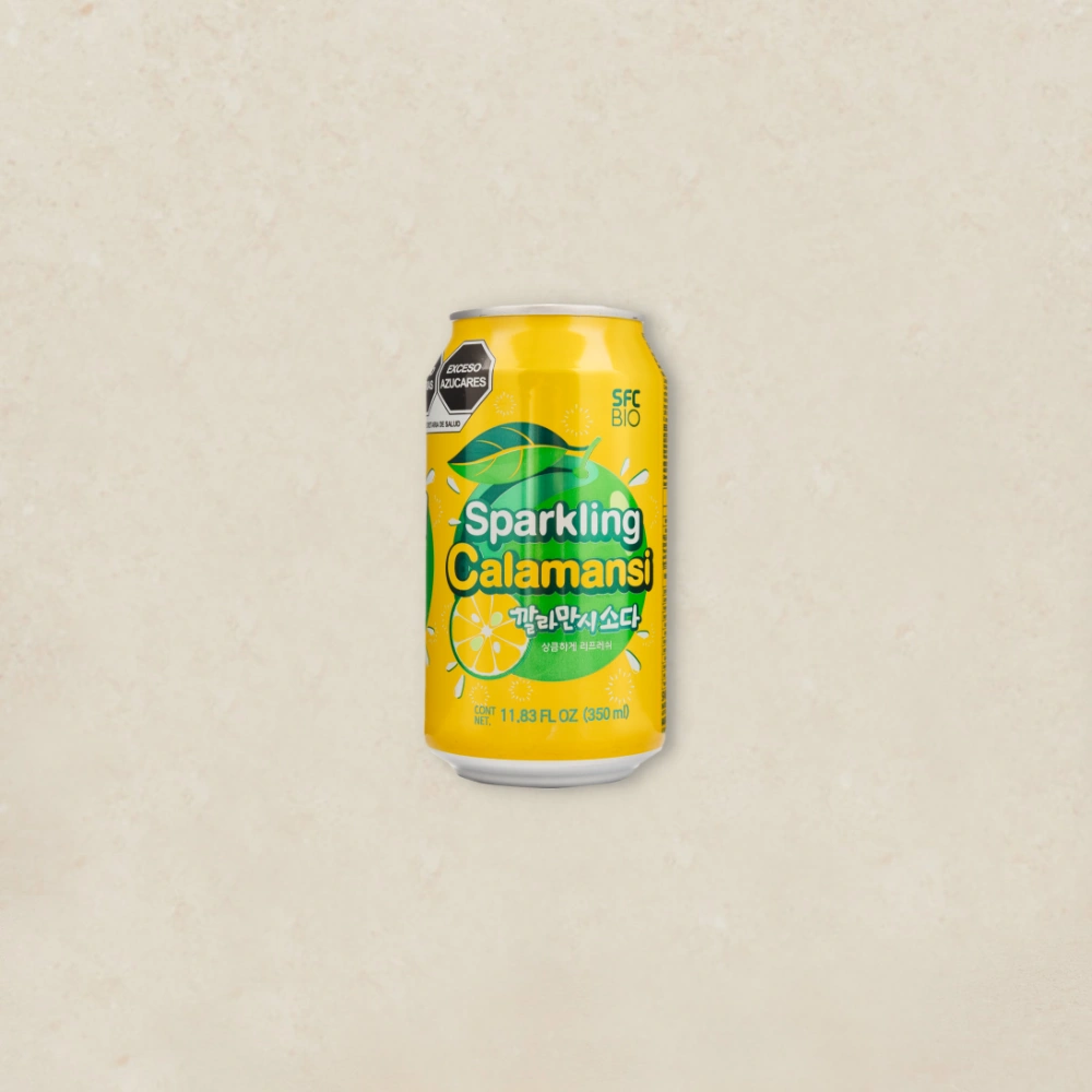 깔라만시 소다 Bright yellow can of Sparkling Calamansi drink with lime slices and leaves, centered on a light textured background.