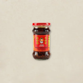Jar of SPICY CHILI CRISP chili paste with a red and yellow label, centered on a pale background.