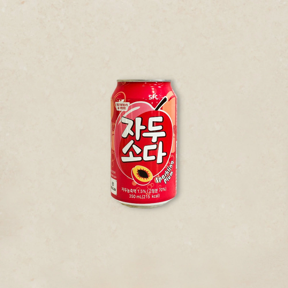자두 소다 Red can of plum soda with Korean text, centered on a light beige background; includes small 'Sparkling Plum' label and a graphic plum image.