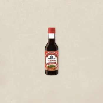 Bottle of Kikkoman Teriyaki Marinade on a light beige background with a red cap visible on top.