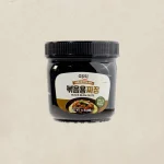 Jar of black bean paste labeled in Korean and English on a beige background.
