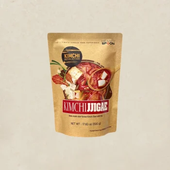 Stand-up pouch of Kimchi Jjigae soup mix with tofu and veggies on beige packaging background, label reads Kimchi Jjigae.