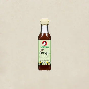 Bottle of Otafuku vegan ponzu sauce with a light-colored cap, centered on a beige textured background, label reads 'Otafuku' and 'Ponzu' on a green panel, product photo.