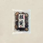 Bag of dried mushrooms in a clear plastic package with a white label and bold black Japanese characters on the front.