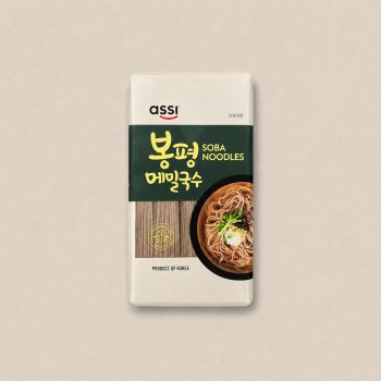 Package of Assi Soba Noodles in a white bag with a dark green label, featuring noodles in a bowl on the right and 'Product of Korea' at the bottom.