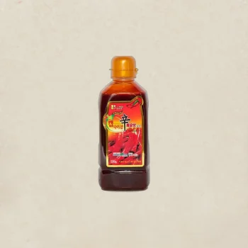 Bottle of Korean chili sauce with an orange cap, centered on a beige background.