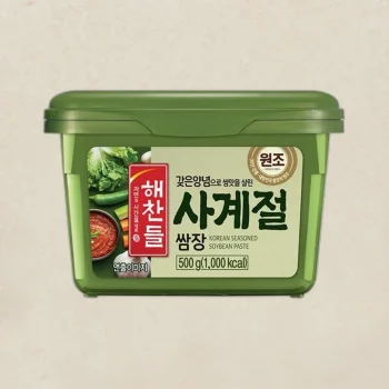 Green plastic tub of Korean soybean paste (doenjang) with a beige label and red vertical Korean text on the front, 500 g package.