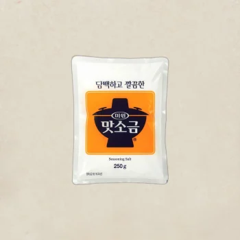 Bag of seasoning salt (250 g) with orange label and Korean text on a beige background.
